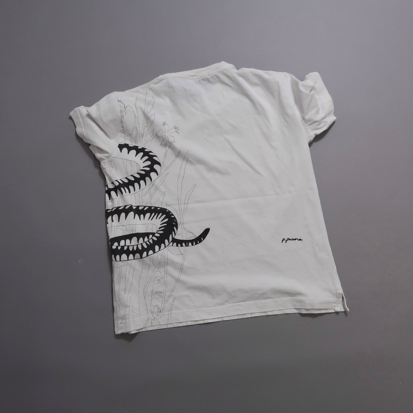 White T-shirt with black snake and floral design on the back.