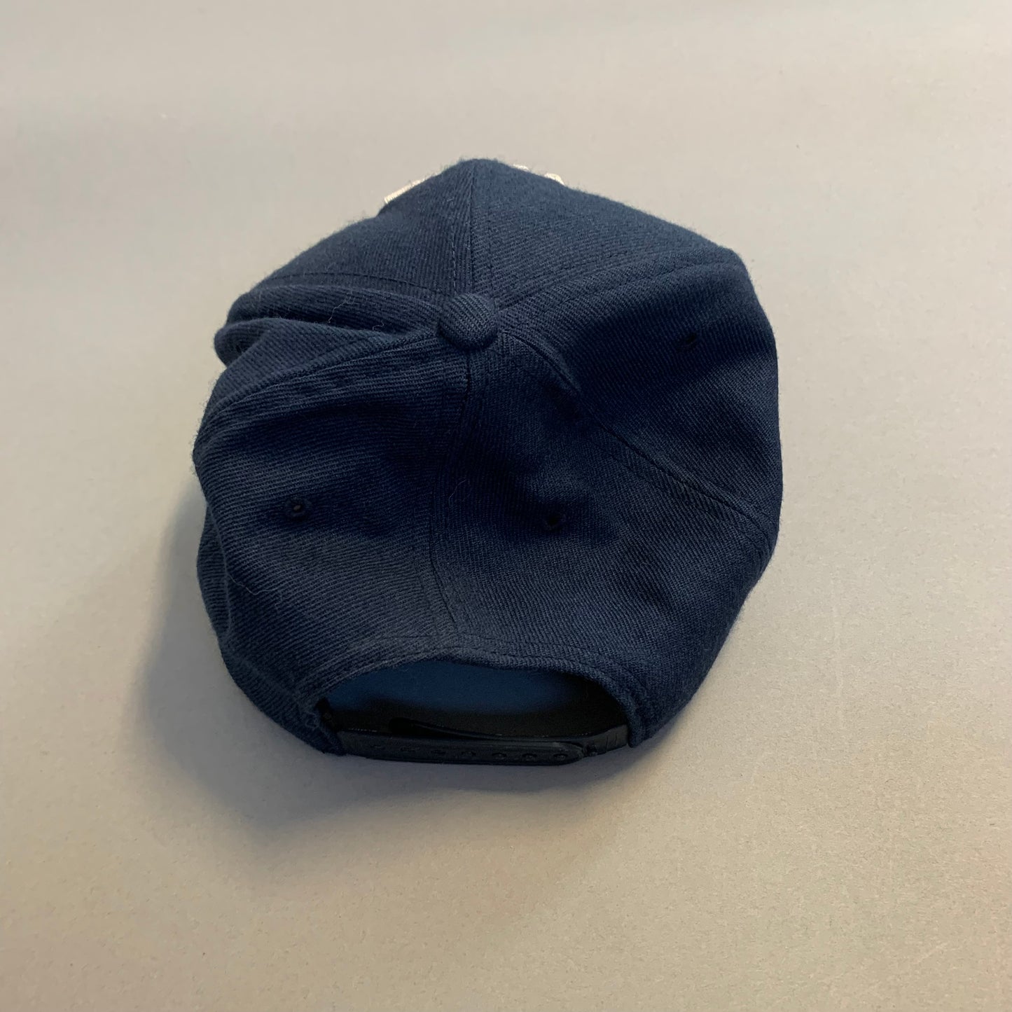 Navy blue cap resting upside down on a light surface.
