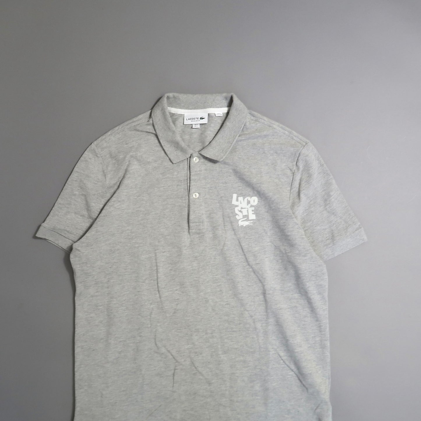 Gray Lacoste polo shirt with white logo on the chest.