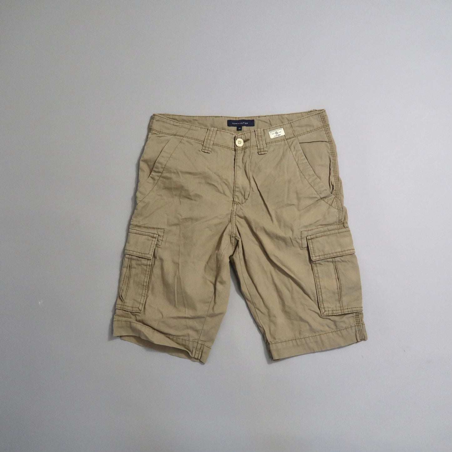 Khaki cargo shorts with multiple pockets on a light gray background.