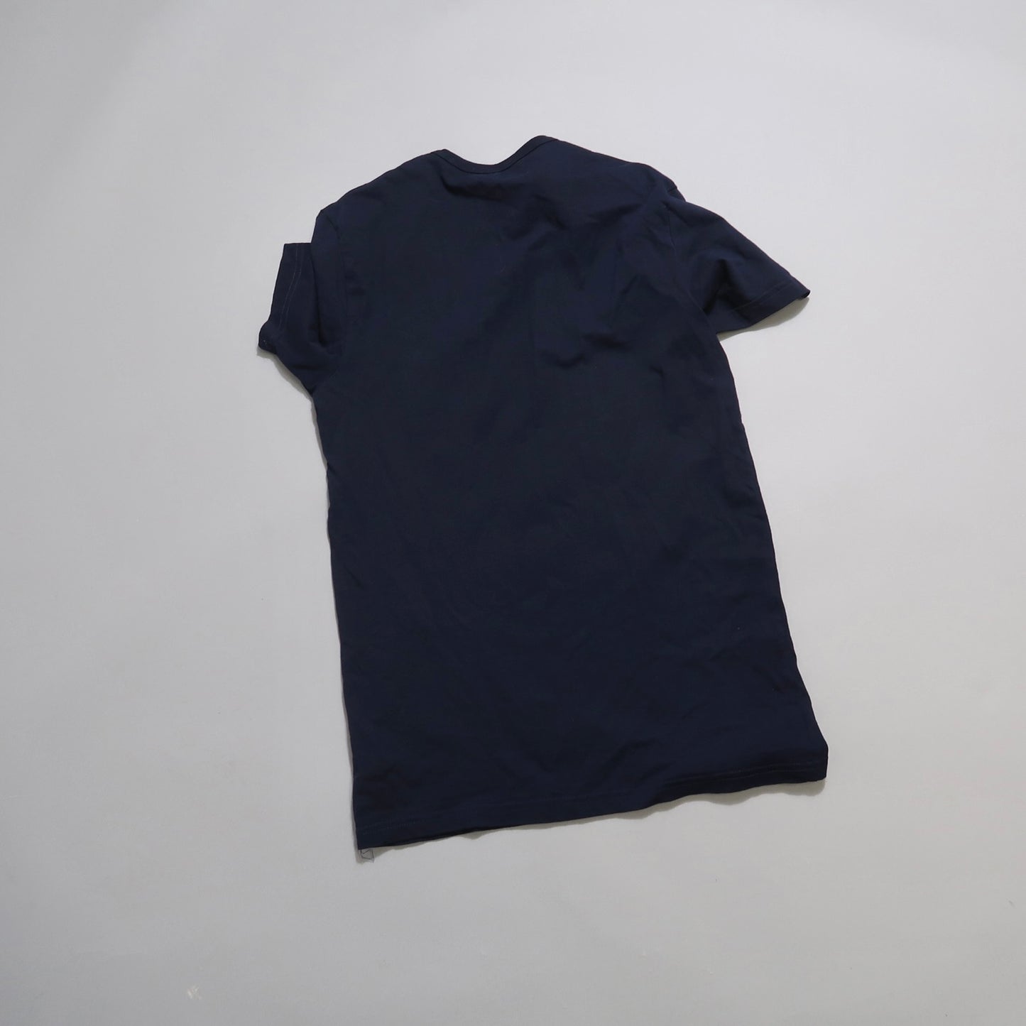 Back view of a black T-shirt on a light gray background.