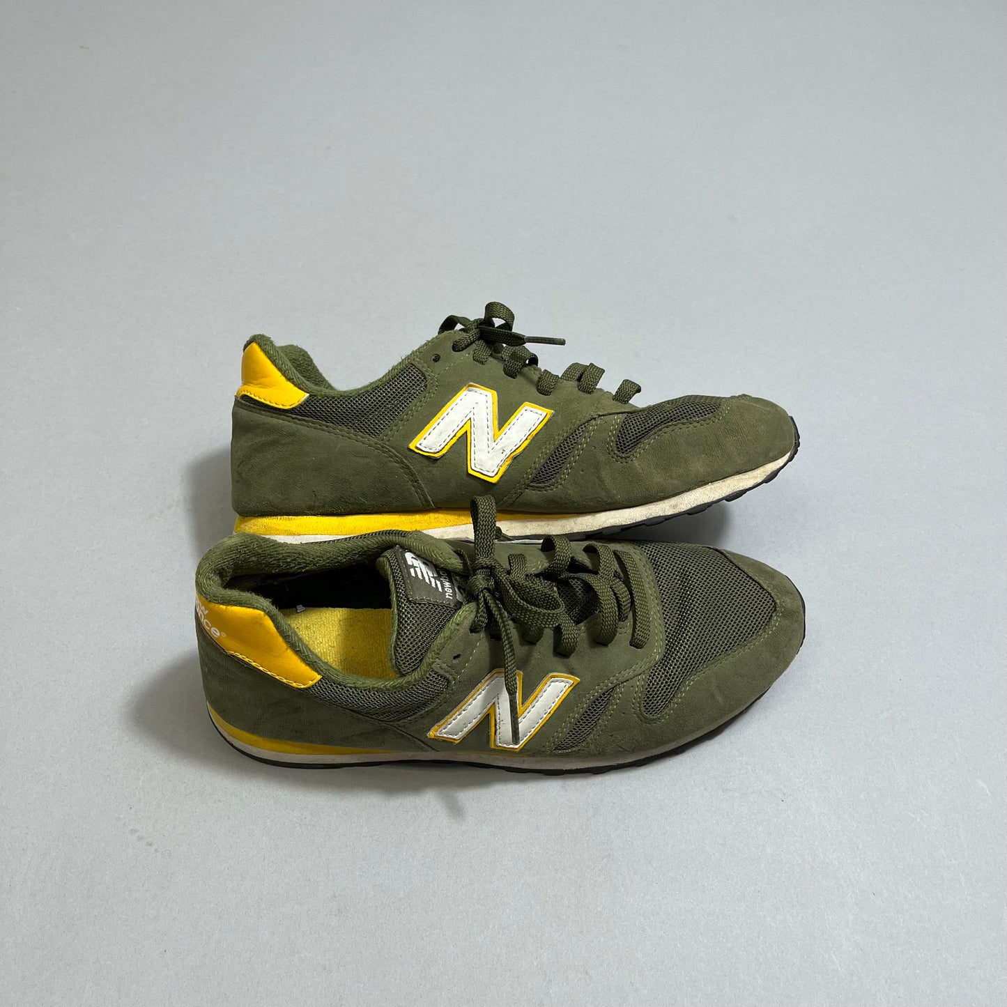 Green and yellow sneakers with nullNnull logo on gray background.