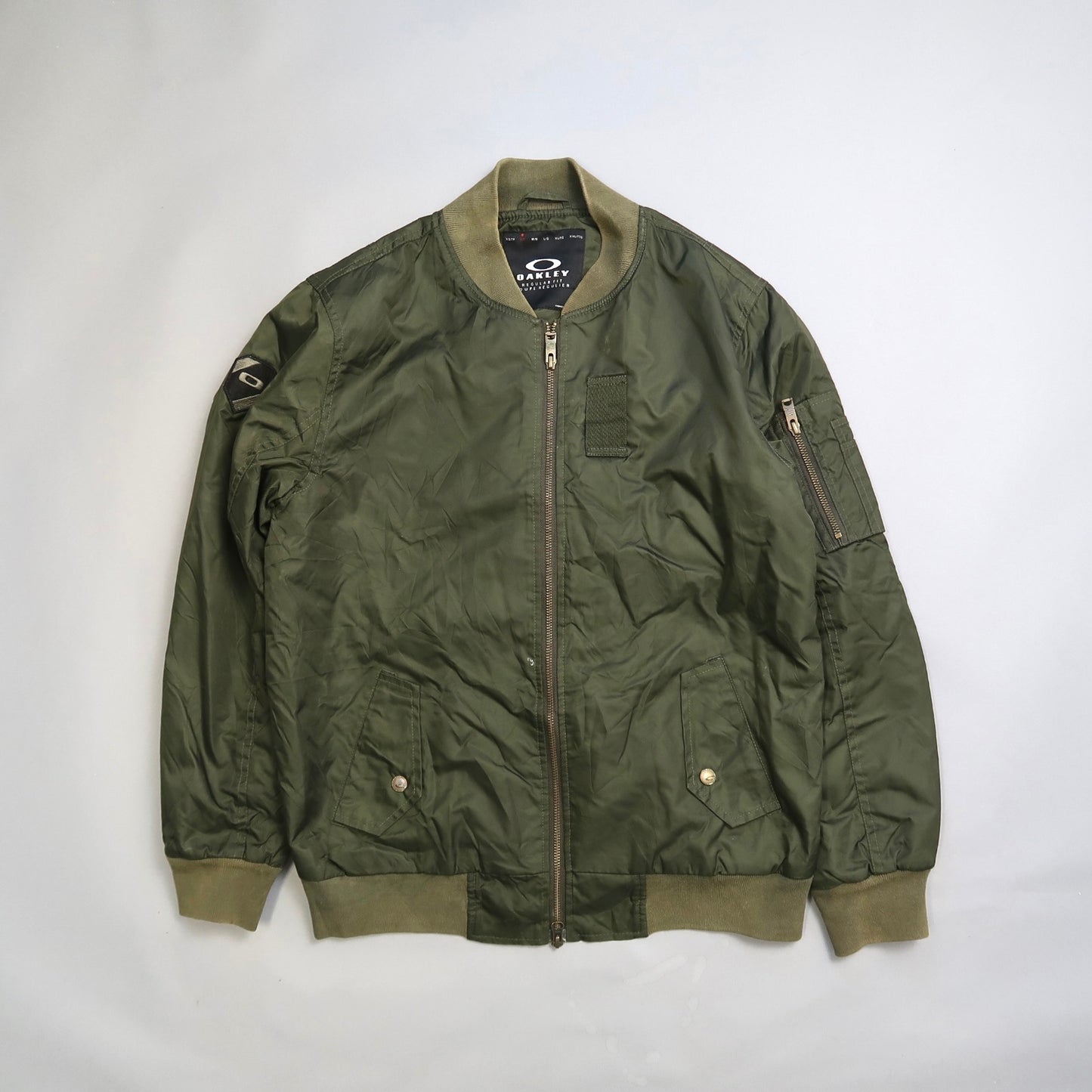 Olive green bomber jacket with zip pockets and patch details.