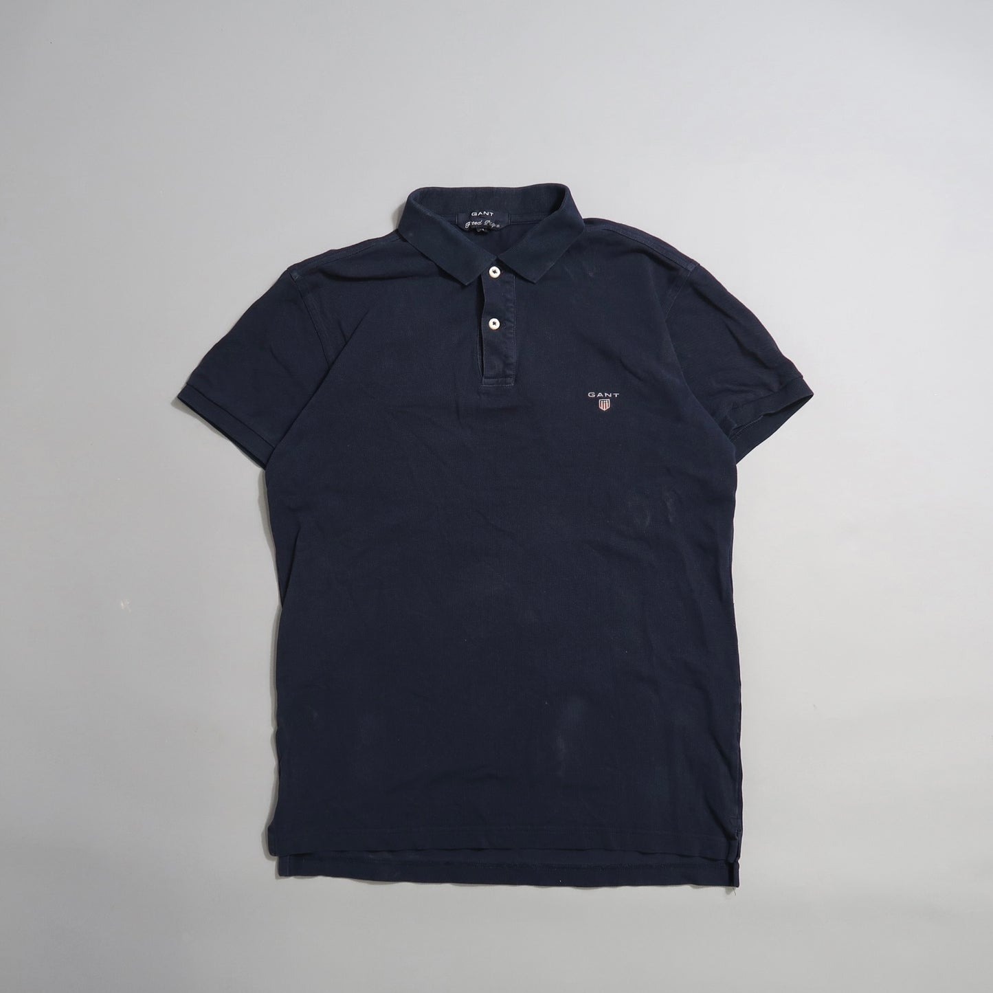 Dark blue polo shirt with a small logo on the chest, laid flat.