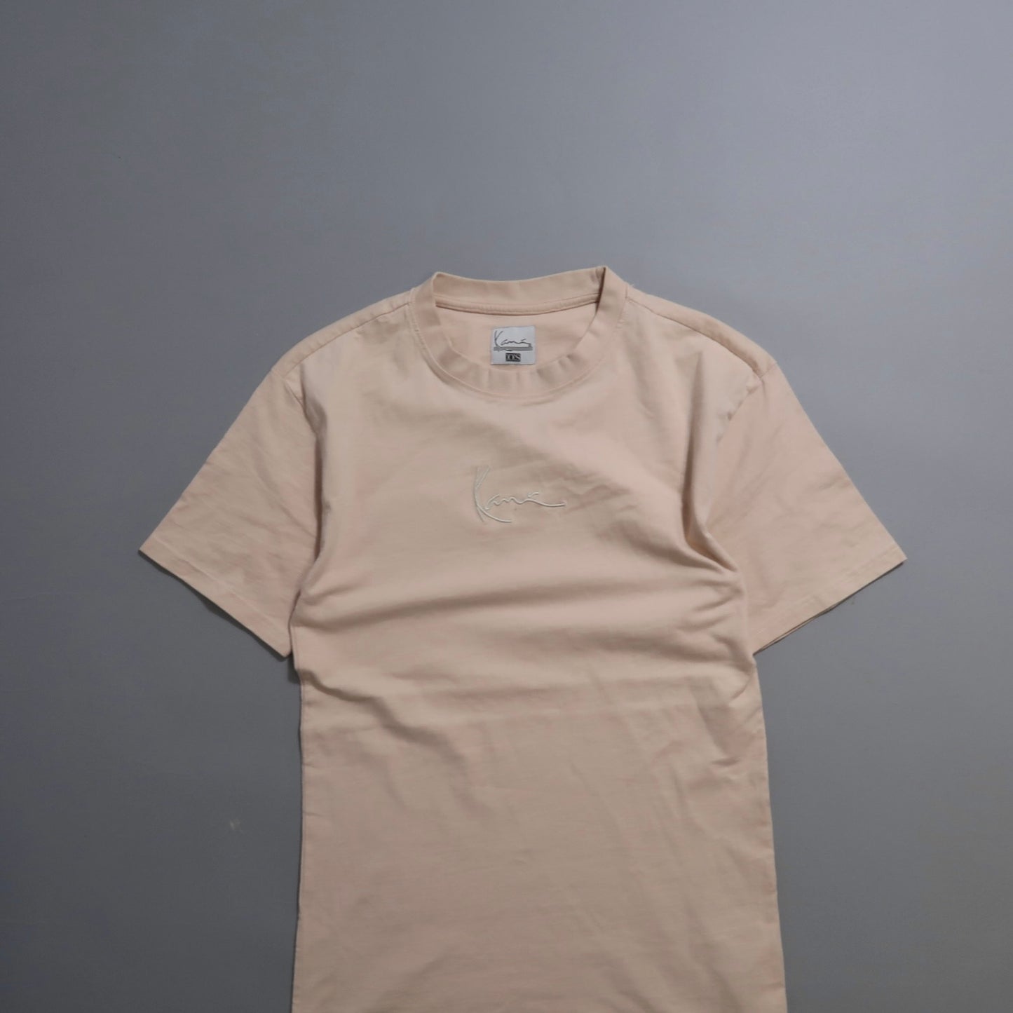 A beige T-shirt with a subtle embroidered design.