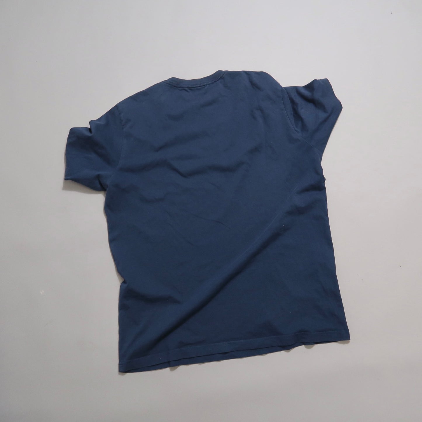 Plain blue T-shirt lying flat on a gray surface.