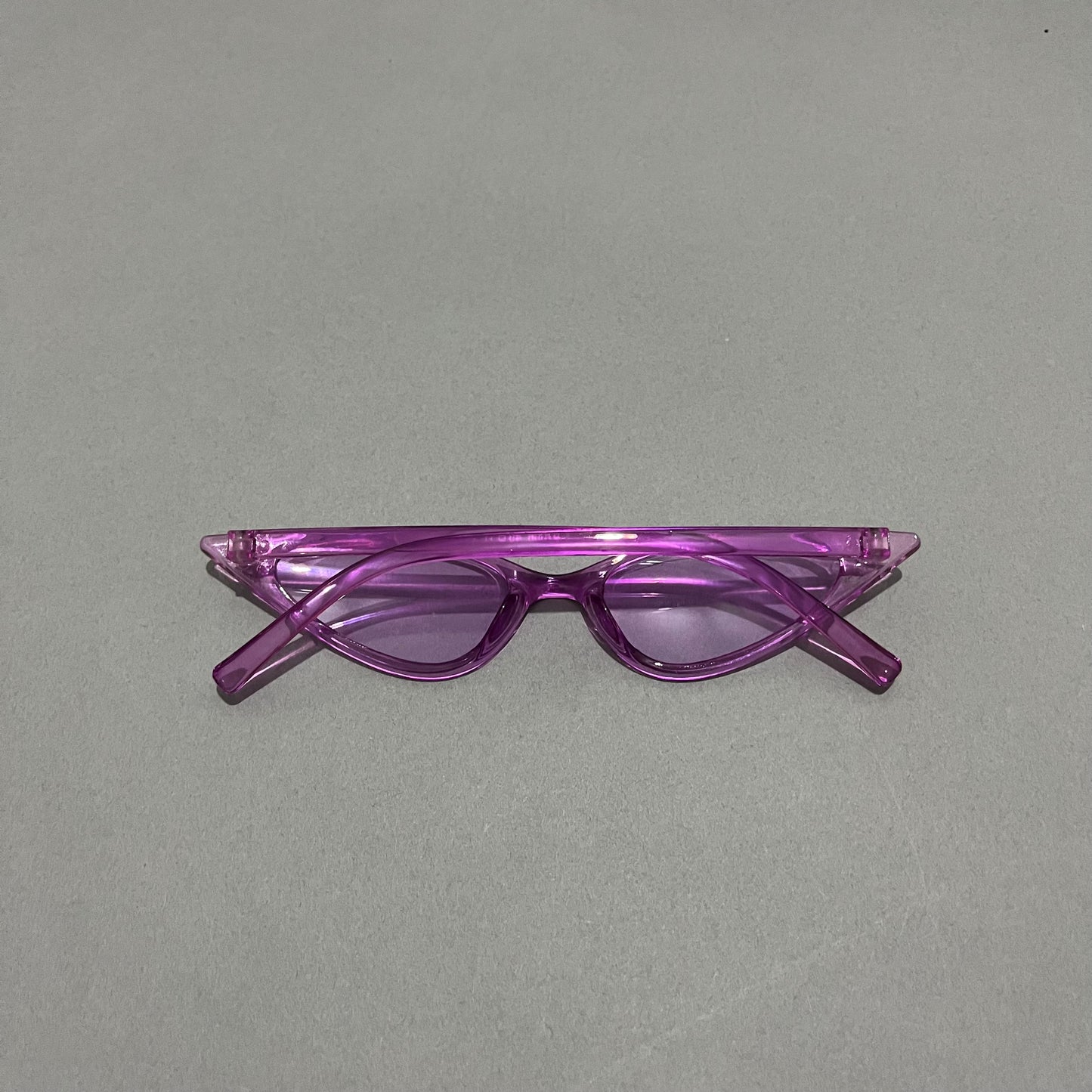 Purple cat-eye sunglasses on a gray background.
