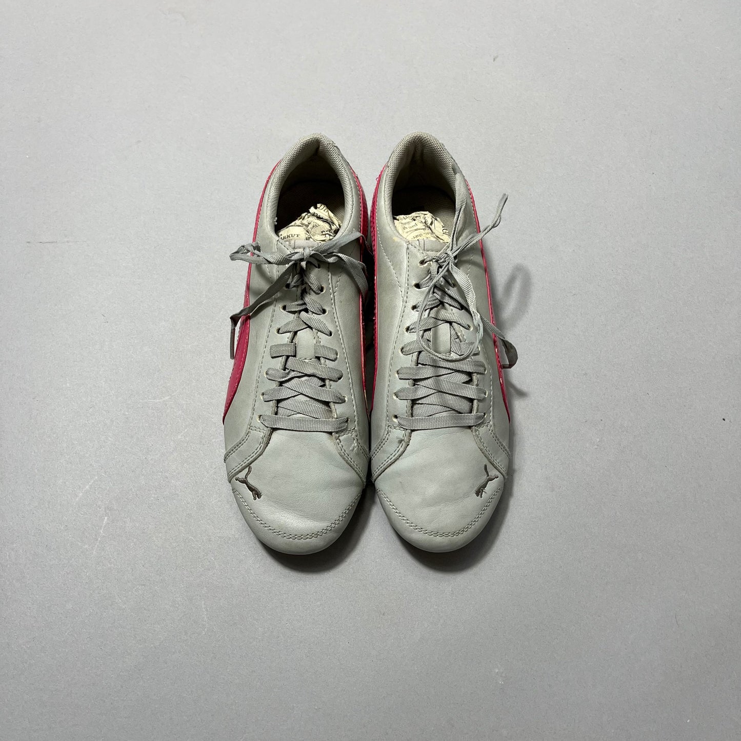 Gray sneakers with pink accents on a plain background.