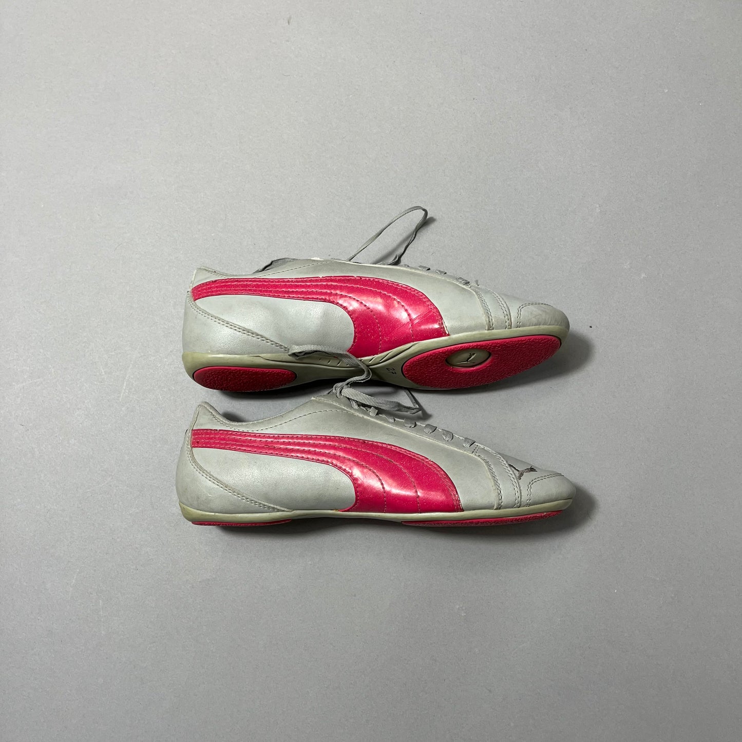 Gray sneakers with pink stripes on a gray background.