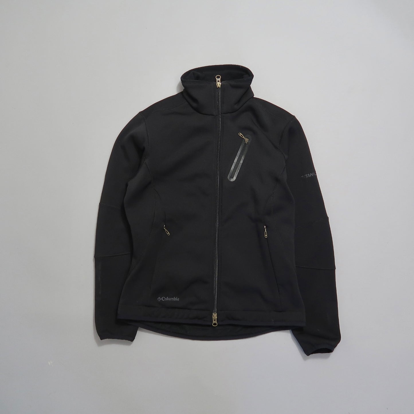 Black Columbia jacket with zipper pockets on a light background.