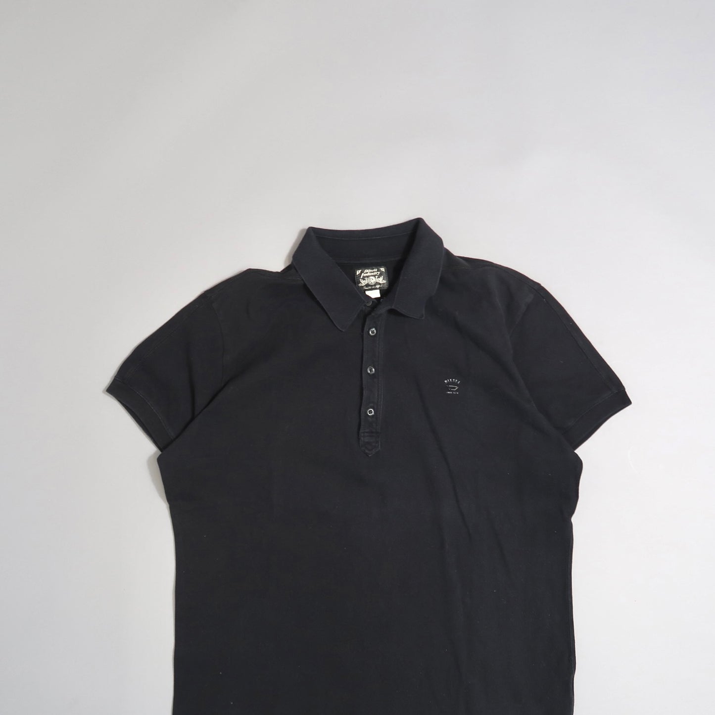 Black polo shirt on a neutral background.
