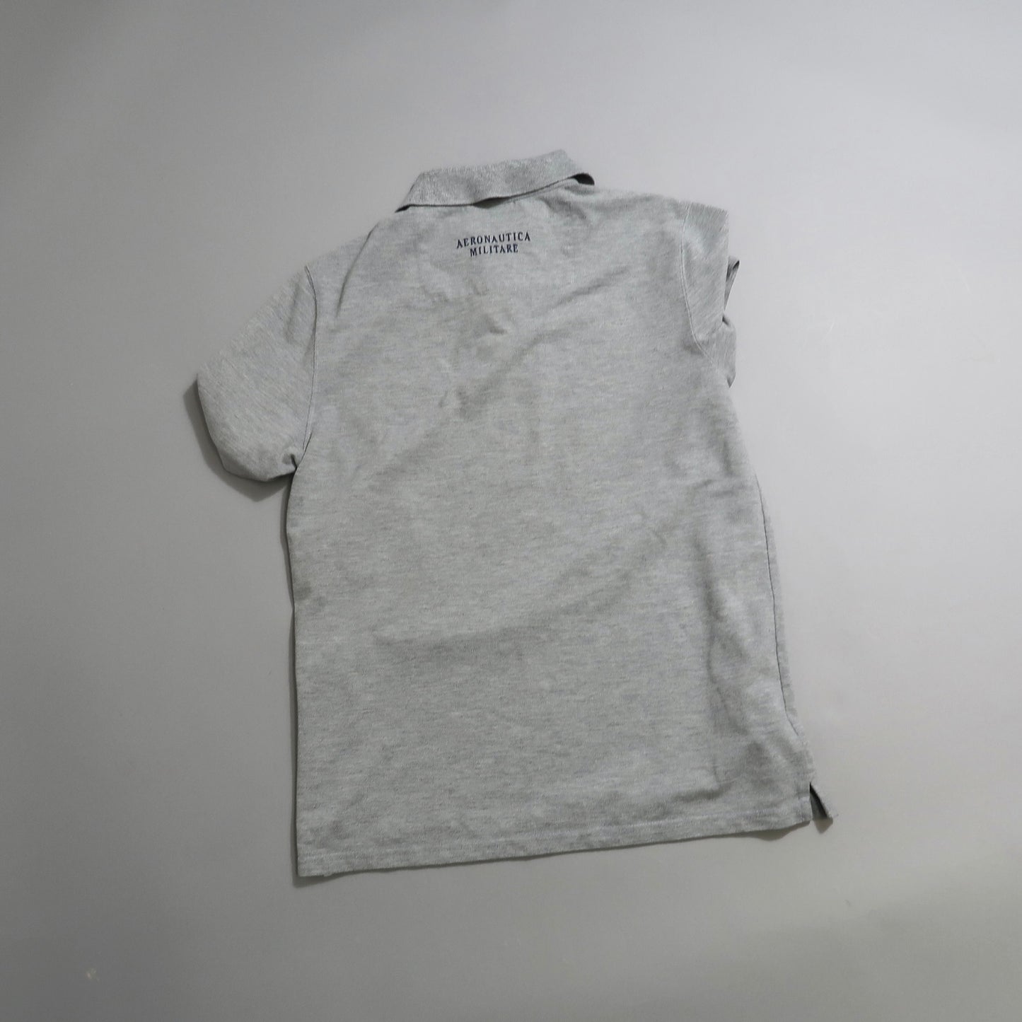 Gray polo shirt laying flat on a surface, back view visible.