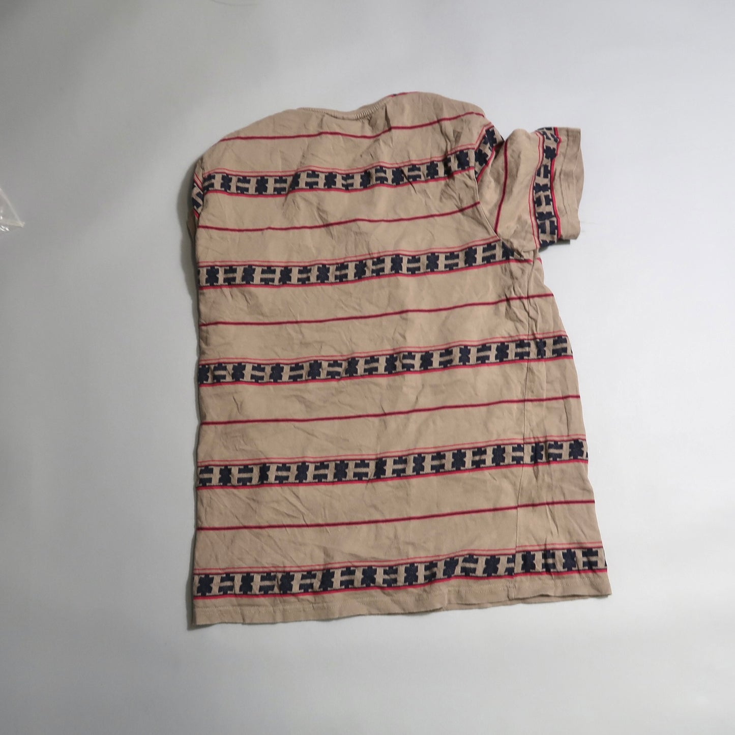 Beige striped shirt with geometric patterns on white background.