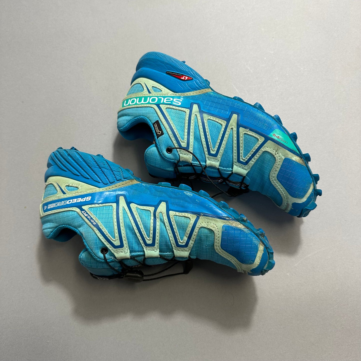 Blue and teal trail running shoes with prominent tread pattern.