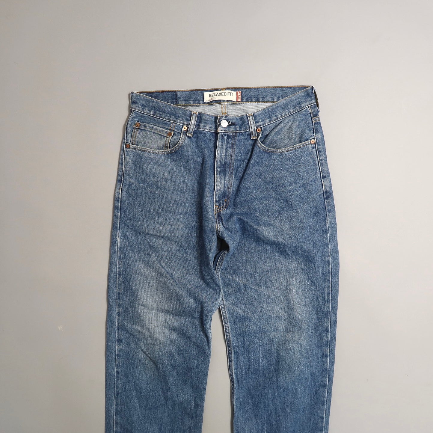 Blue relaxed fit jeans on a plain light gray background.