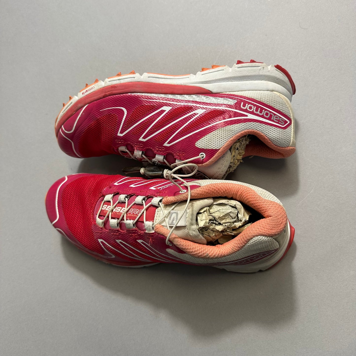 Pink trail running shoes with soles showing wear and tear.
