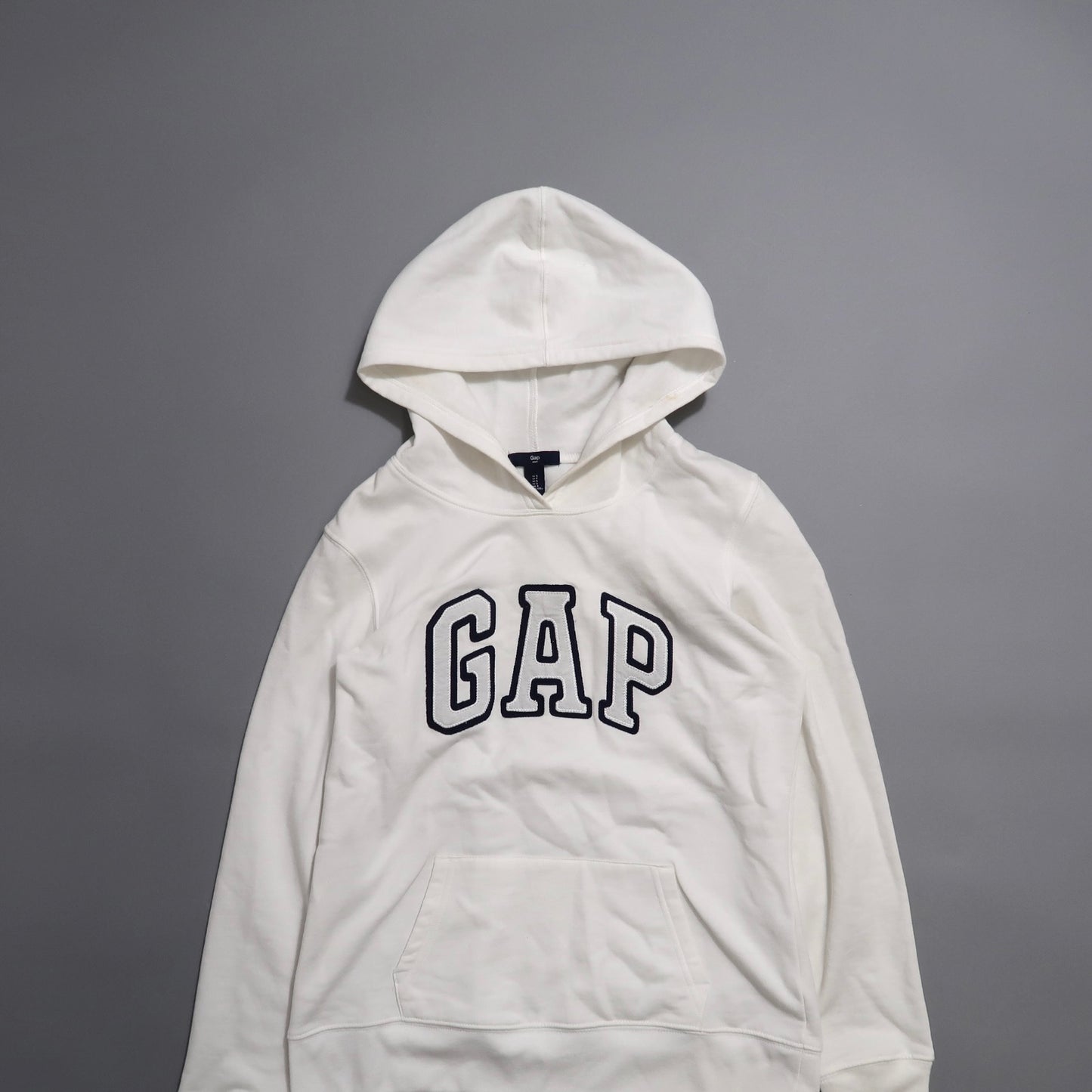 White GAP hoodie on a gray background.