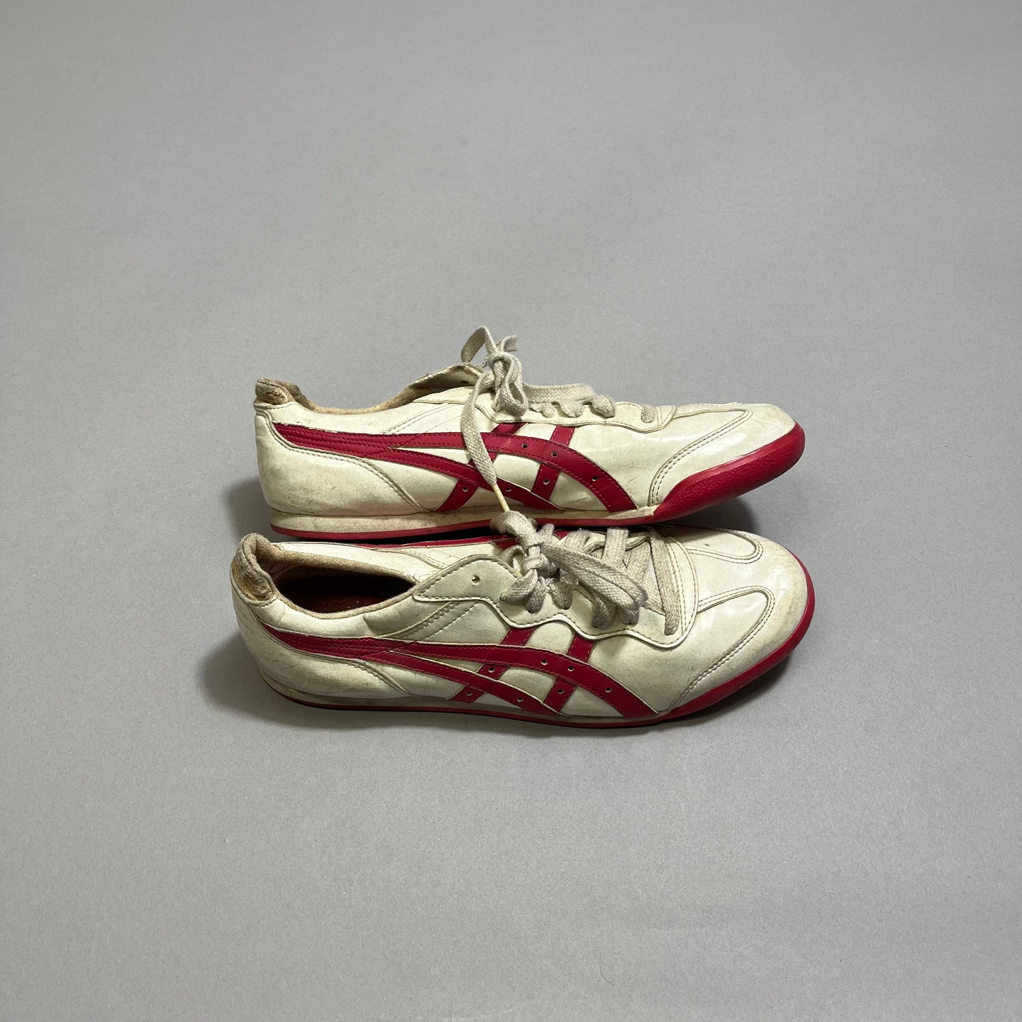 White sneakers with red stripes on a gray surface.