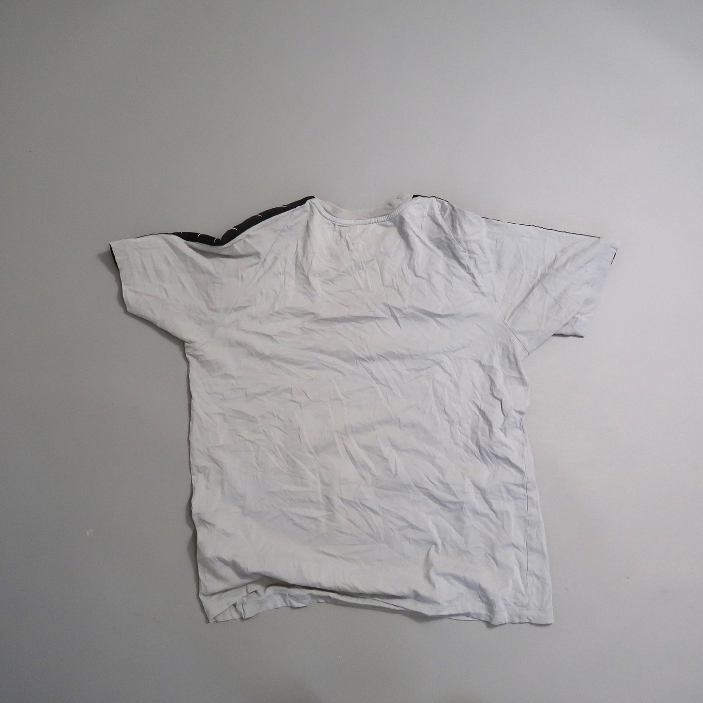 Wrinkled white T-shirt on a gray background.