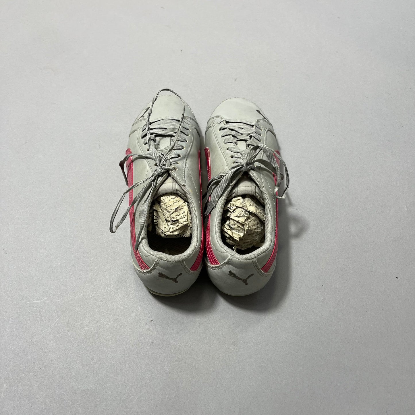 Gray sneakers with pink accents, stuffed with crumpled paper.