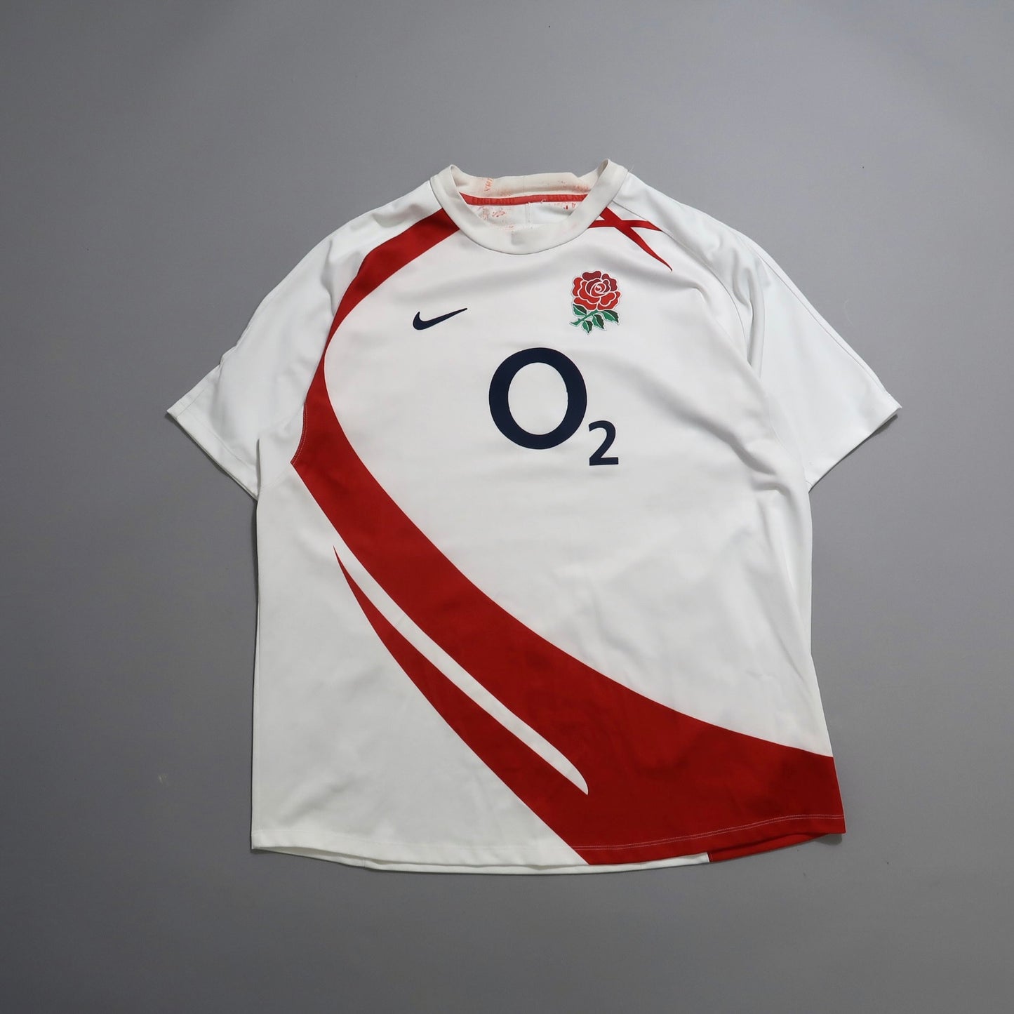 White sports jersey with red swoosh and logo on chest.