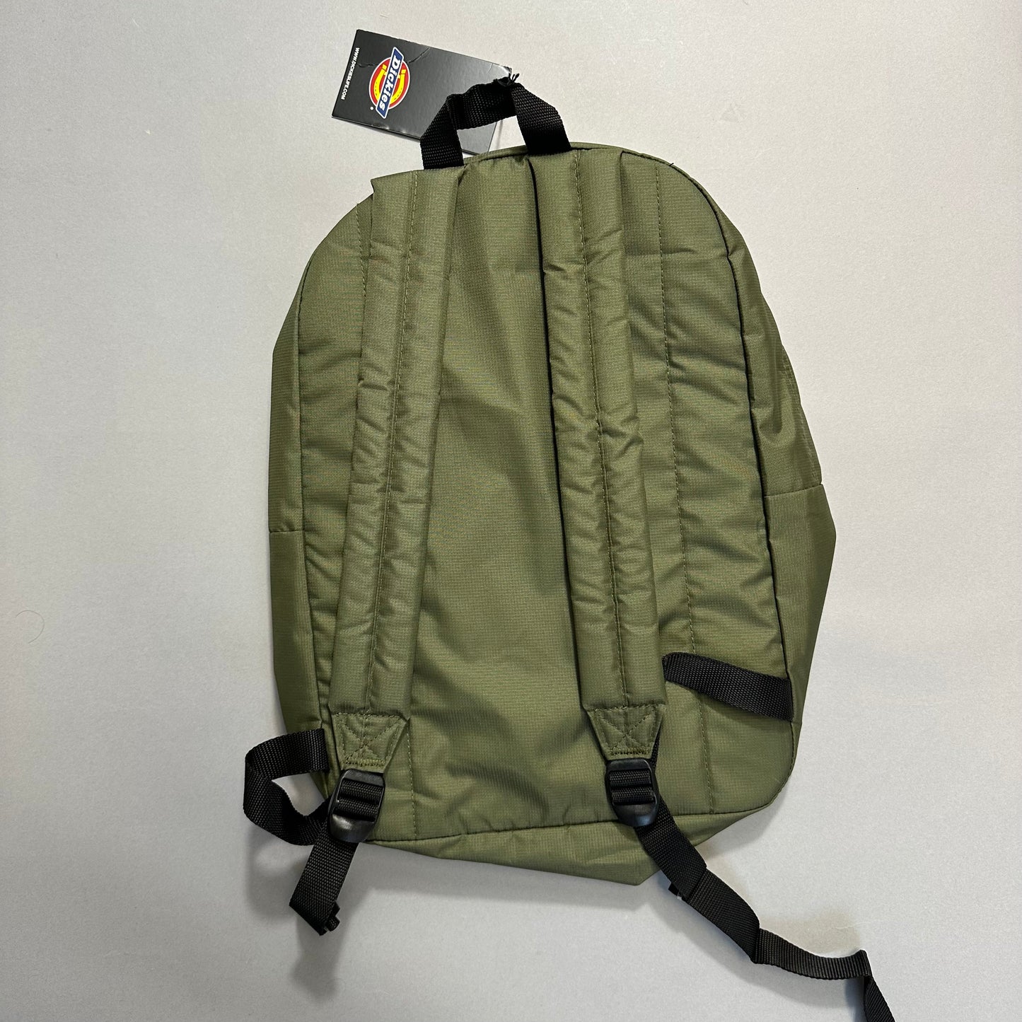 Green backpack with black straps and a tag attached on top.