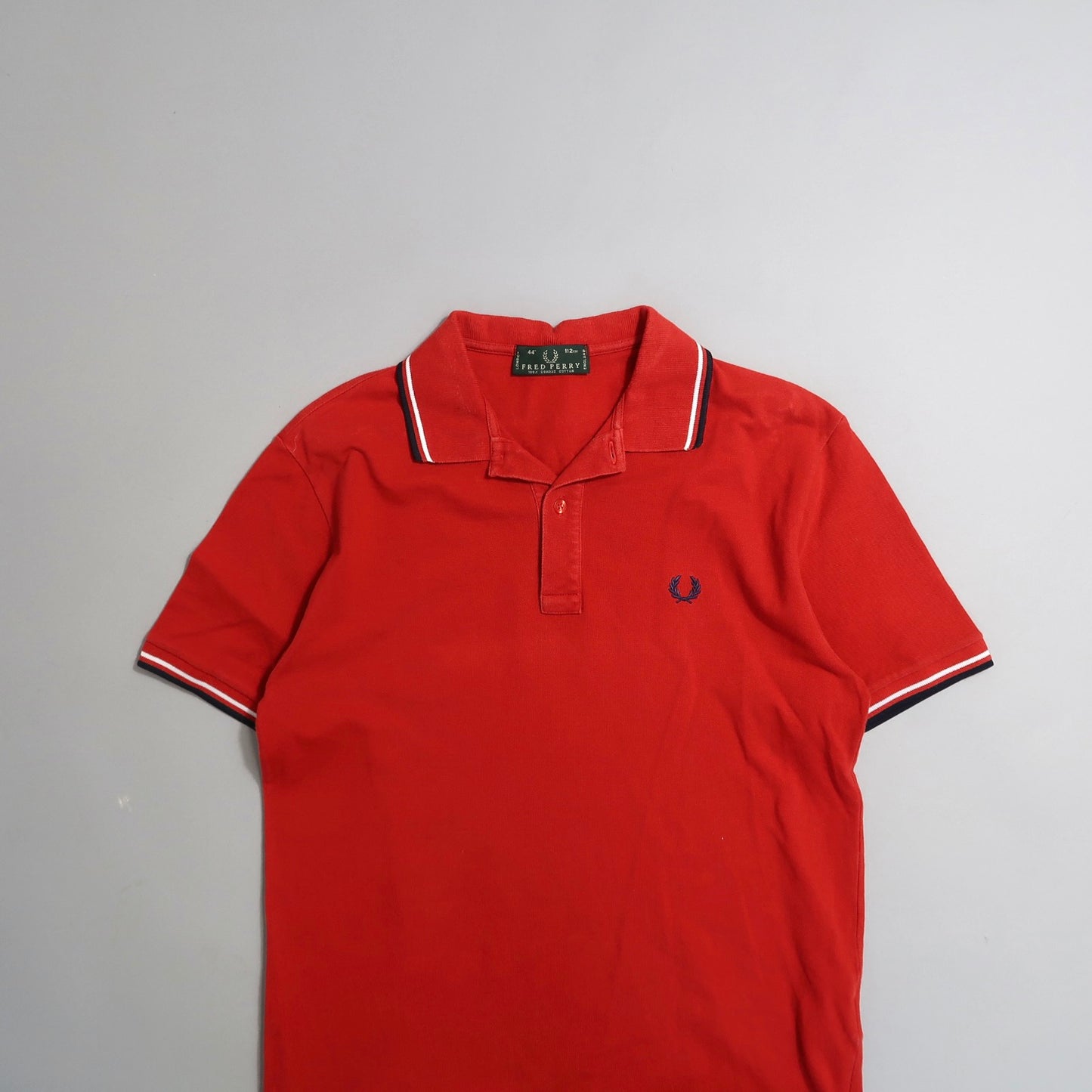 Red polo shirt with striped collar and embroidered logo.
