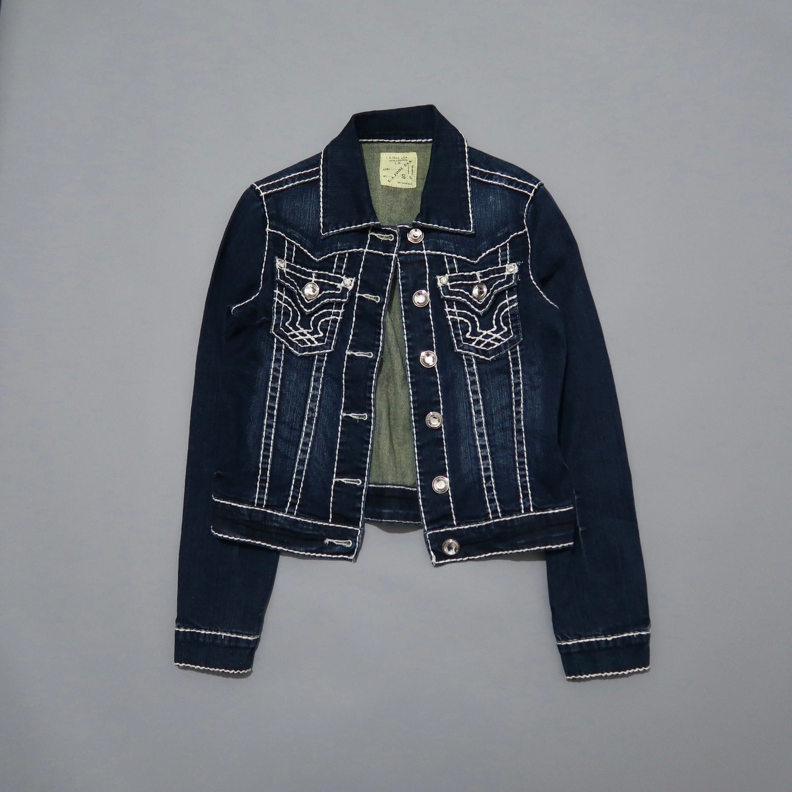 Dark denim jacket with white stitching on gray background.