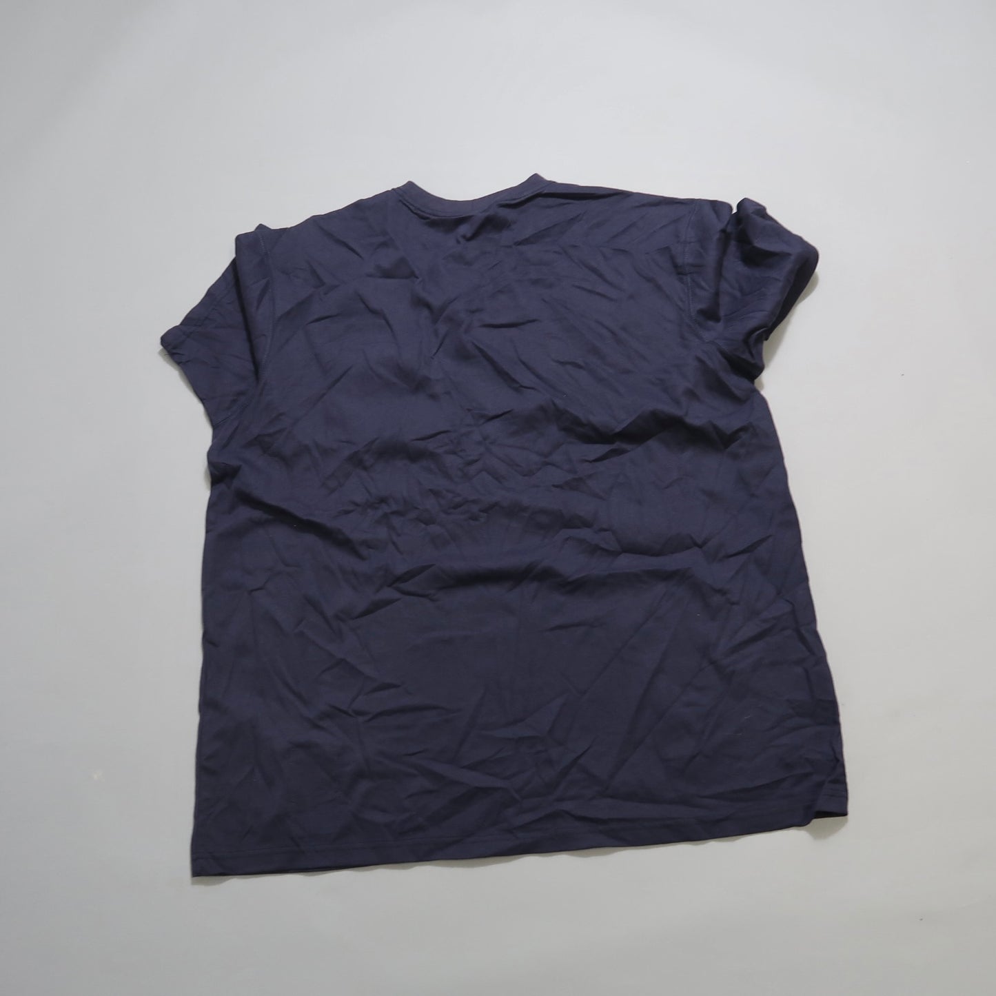 Wrinkled navy blue t-shirt displayed on a flat surface.