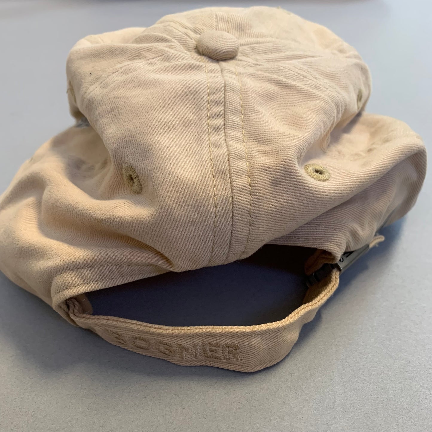 Worn beige cap on a light gray surface.