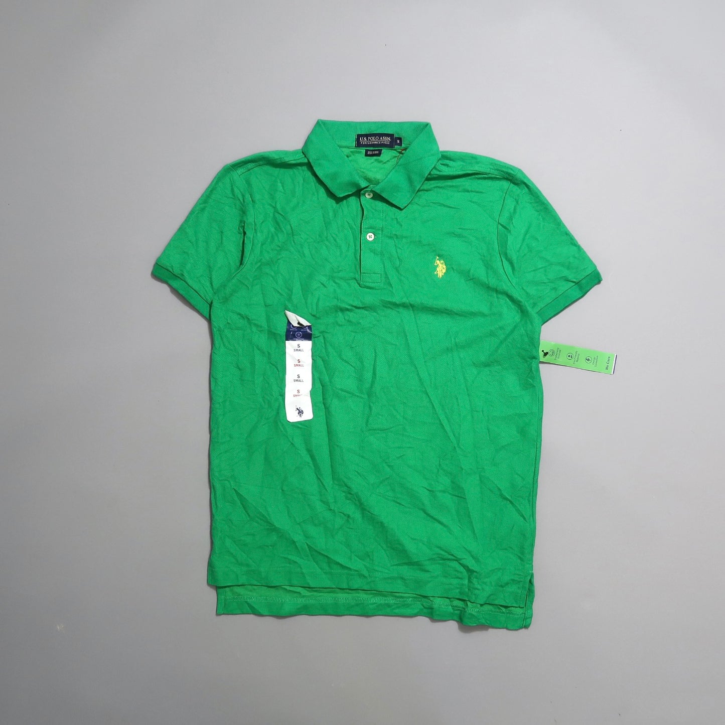 Green polo shirt with collar and logo, laid flat with tags attached.