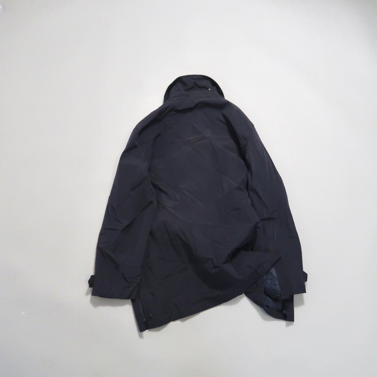 Black jacket lying flat on a light surface.