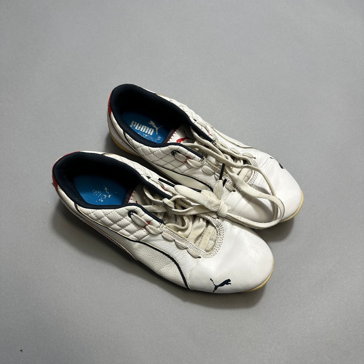 White Puma sneakers with blue insoles on a gray background.