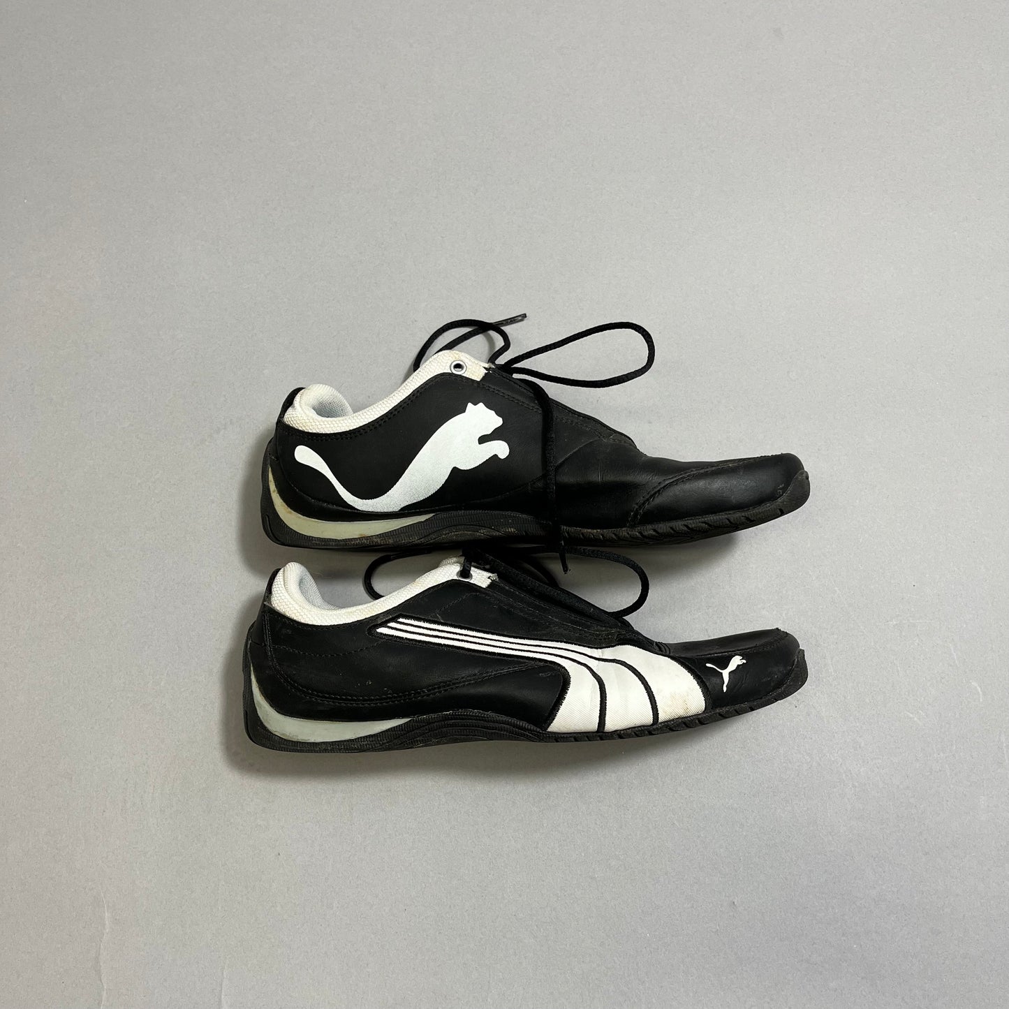 Two black sneakers with white logos on a gray background.