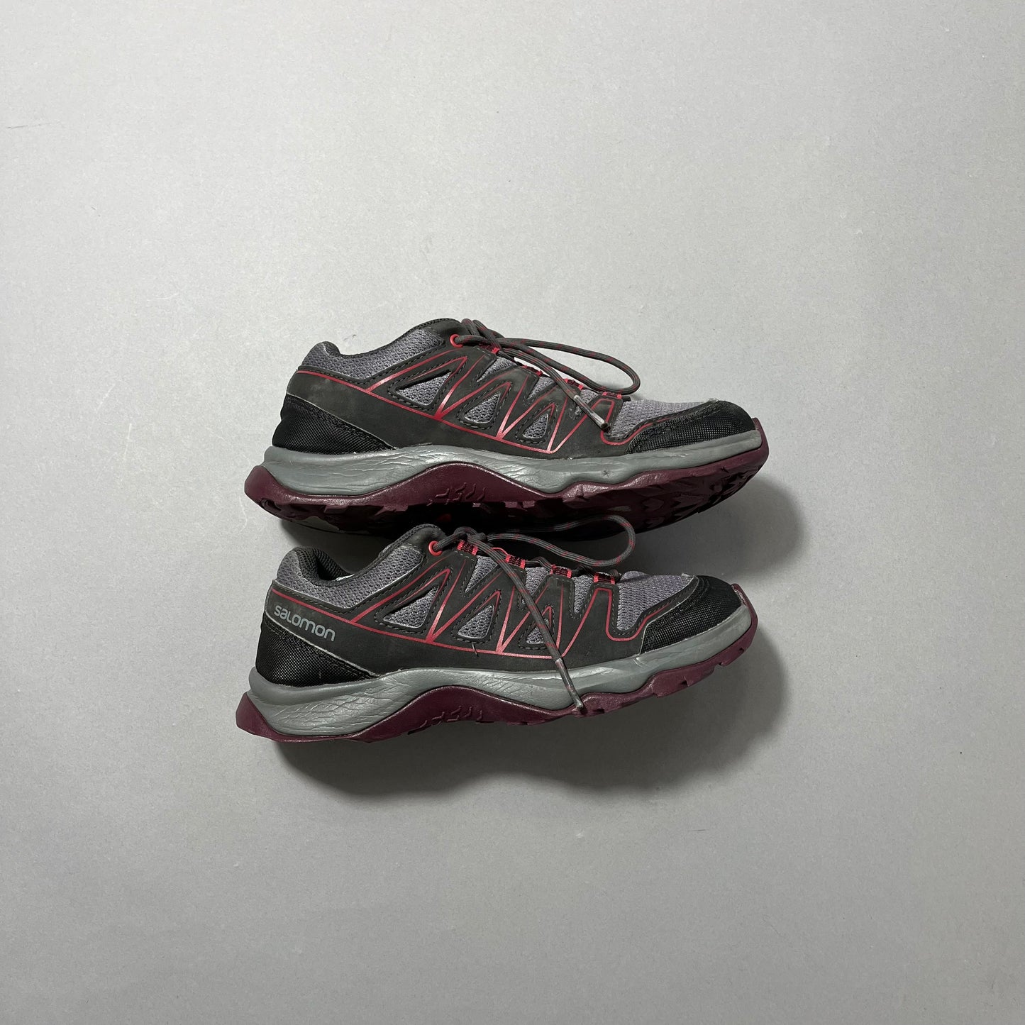 Trail running shoes with gray, red, and black design.