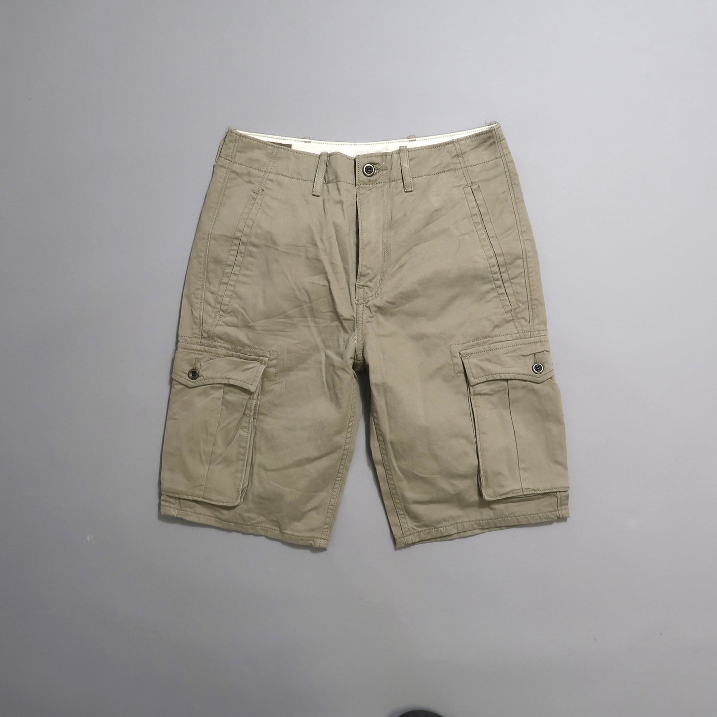 Khaki cargo shorts with multiple pockets on a plain background.