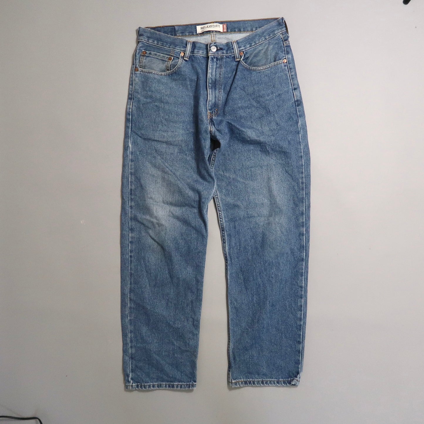 Blue relaxed-fit jeans on a gray background.