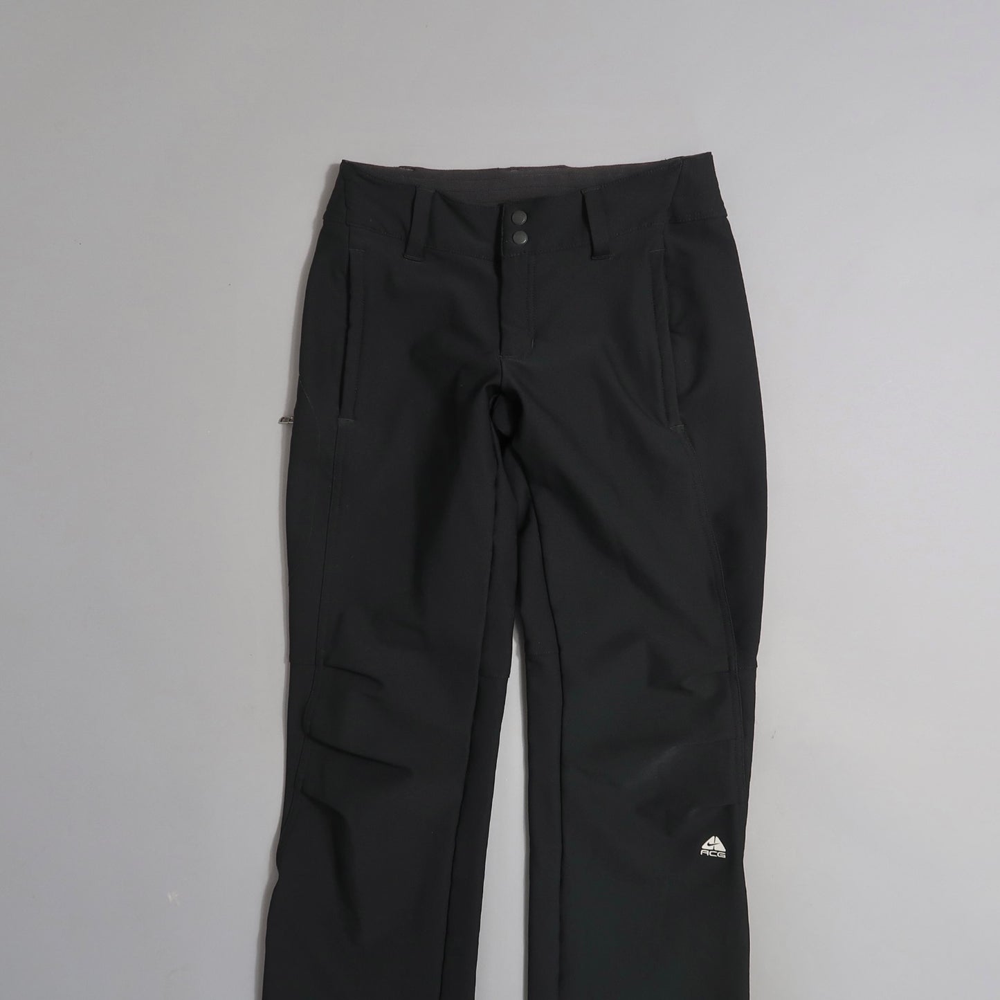 Black pants with front pockets and buttons, displayed on a flat surface.