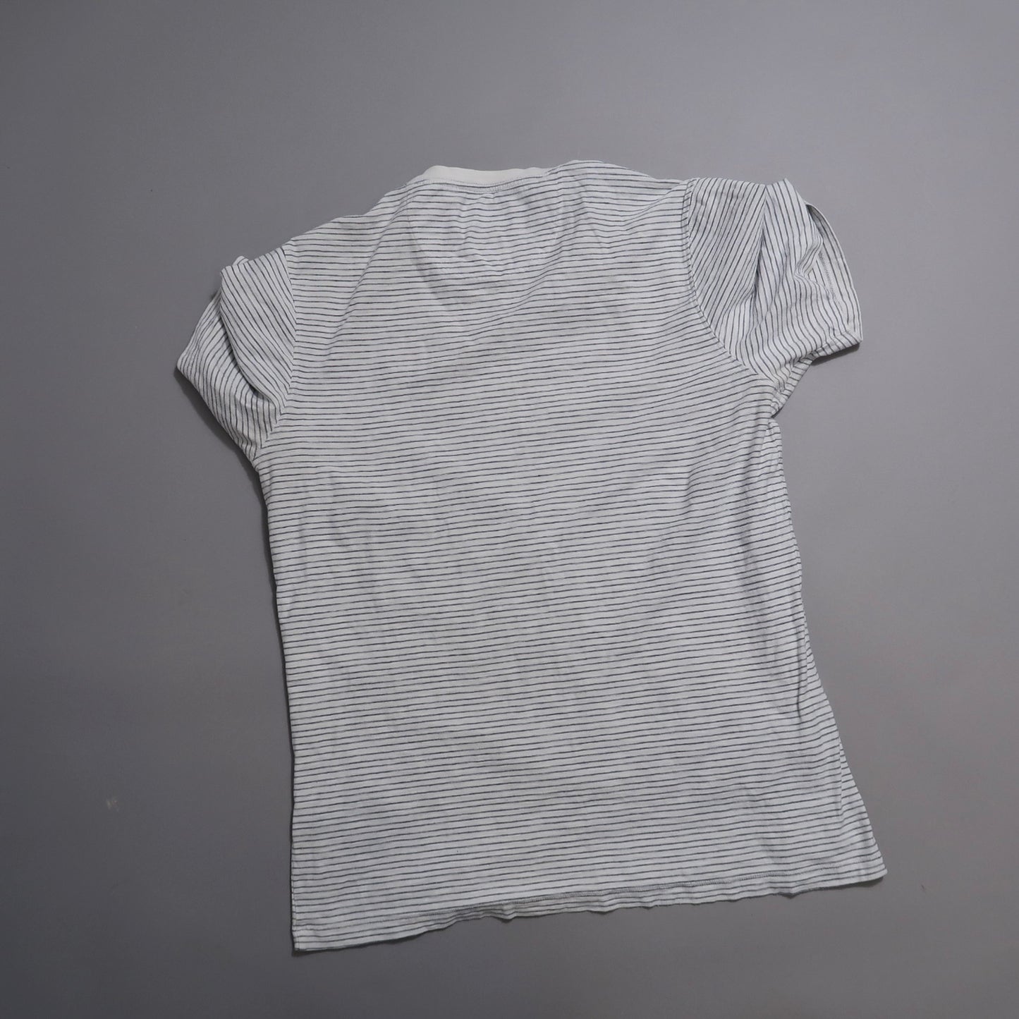 White and black striped T-shirt laid flat, back view.