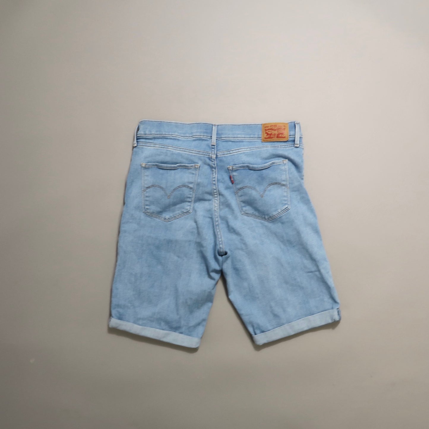 Back view of light blue denim shorts with rolled cuffs.