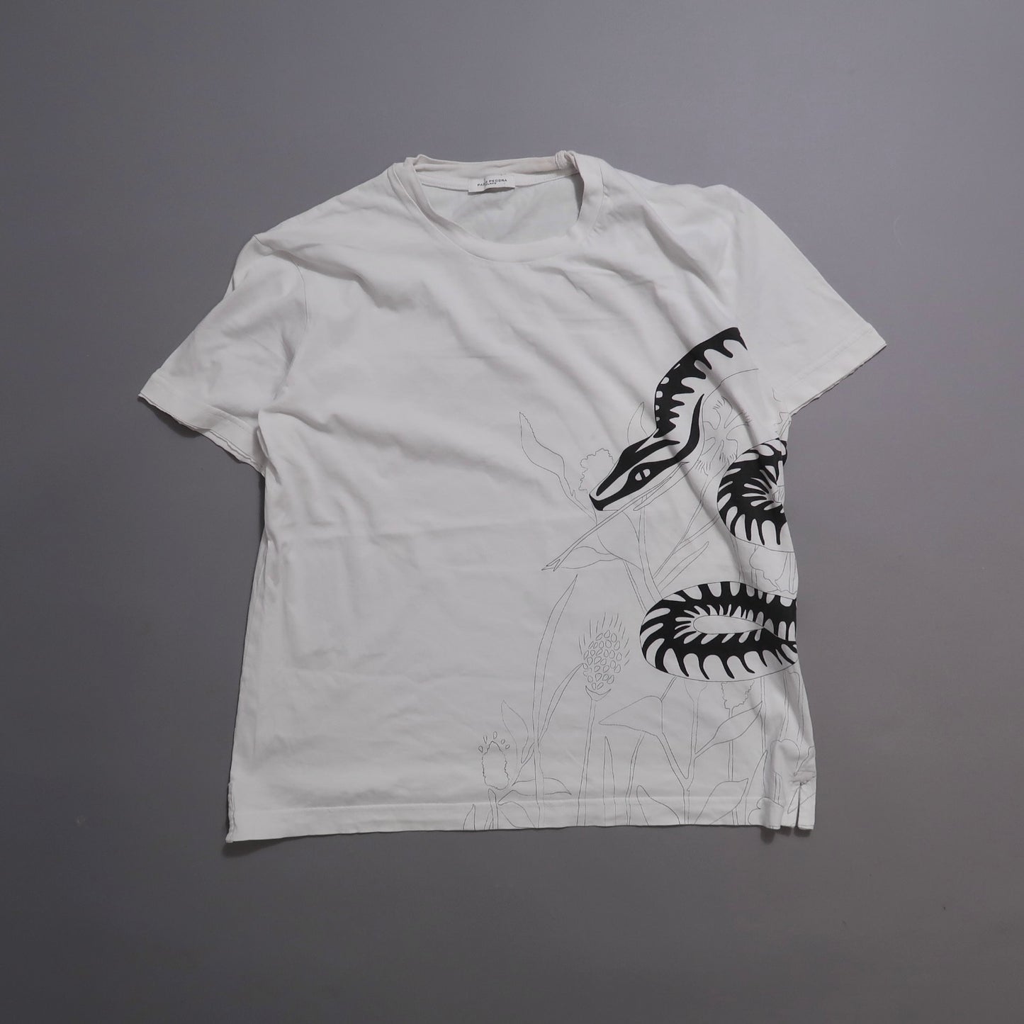 White T-shirt with a black and white snake design on the side.