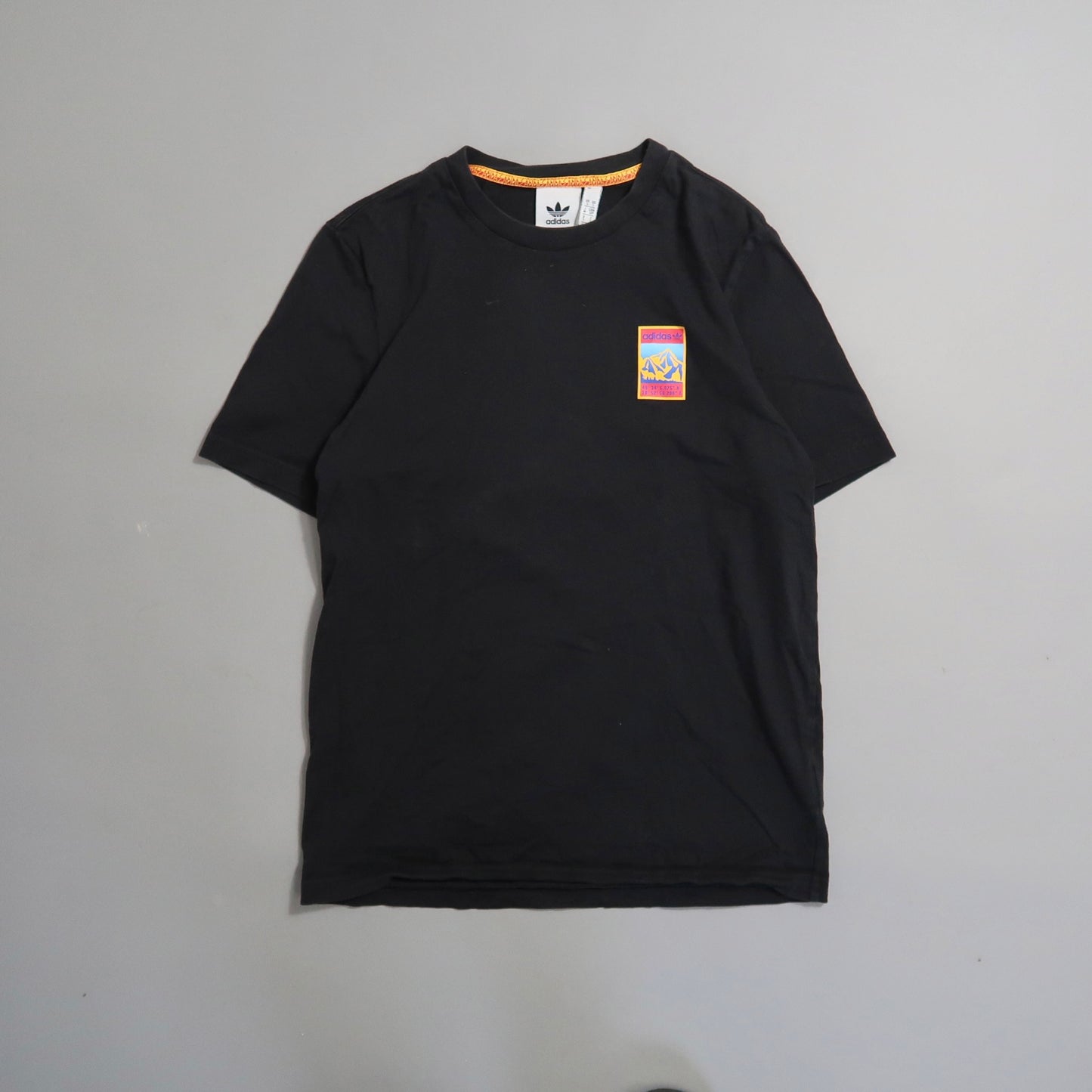 Black T-shirt with colorful logo patch on the front.