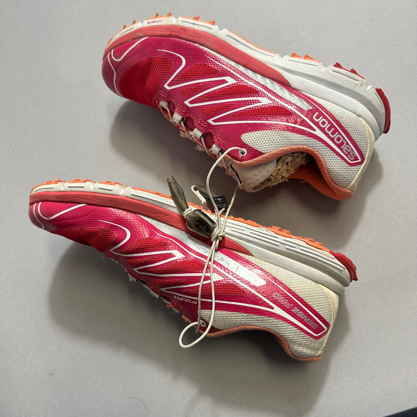 Red and white trail running sneakers with worn soles.