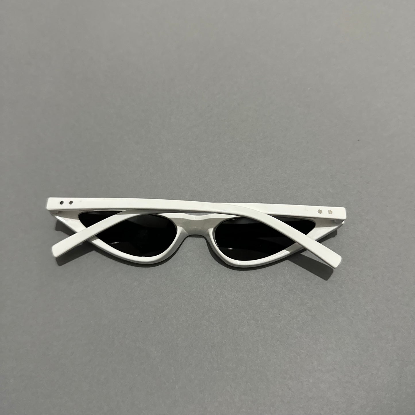 White cat-eye sunglasses on a gray background.