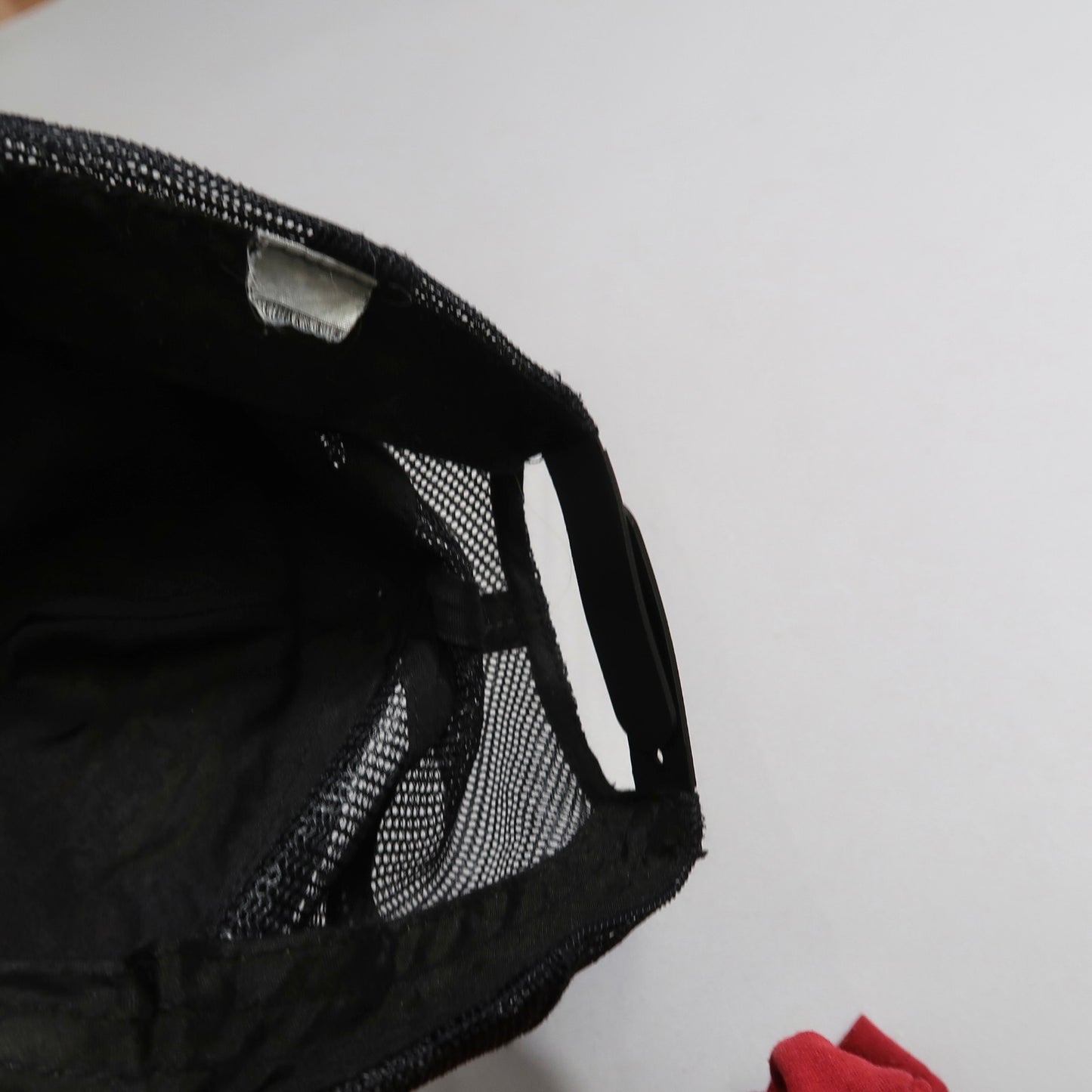Black mesh bag with red cloth on white background.