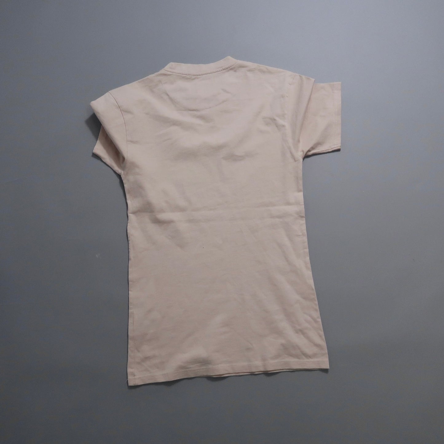 Beige T-shirt laid flat on a gray background.