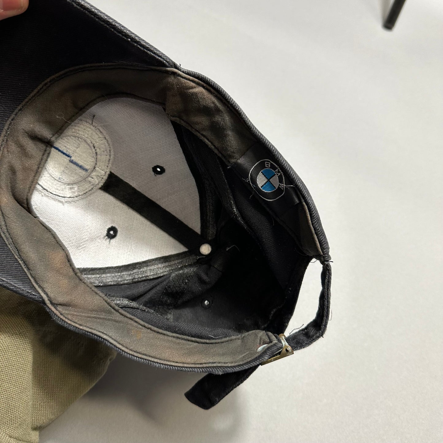 Inside view of a black BMW cap showing logo and interior details.