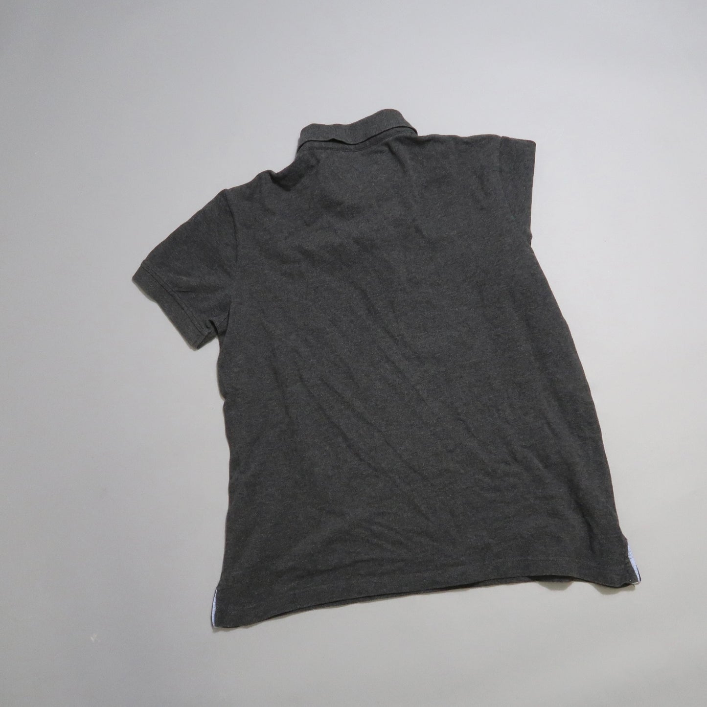 Dark gray polo shirt lying flat on a light surface.
