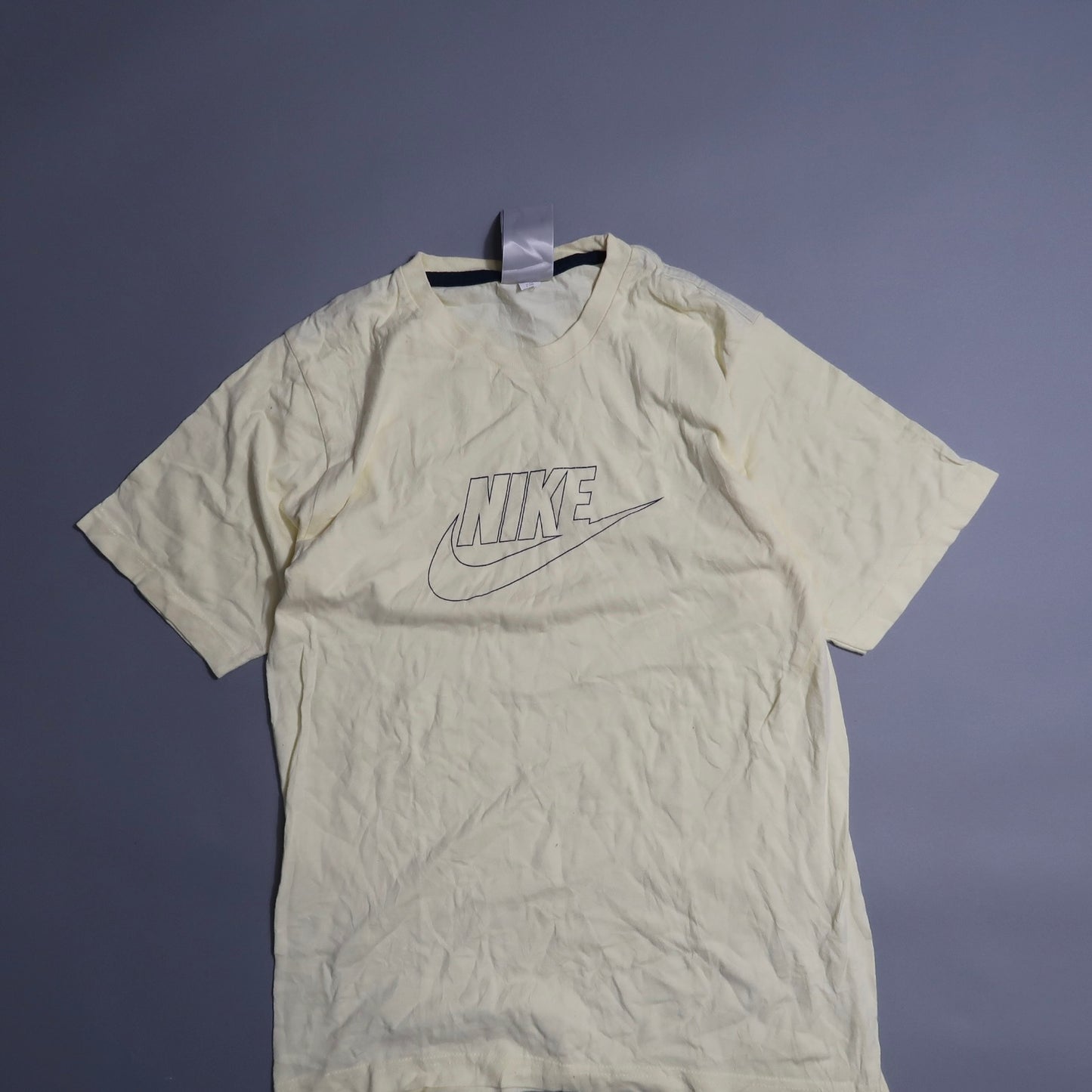 Cream Nike T-shirt with logo on plain background.