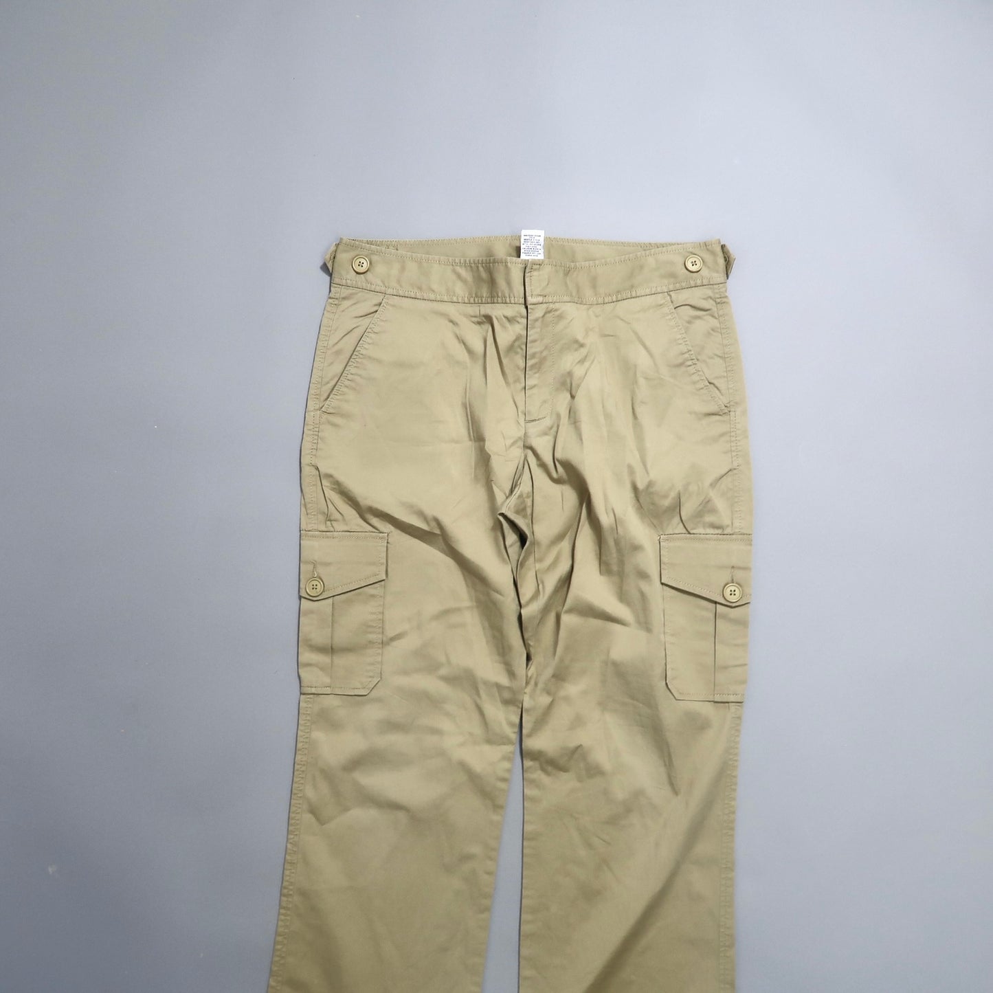 Khaki cargo pants with buttoned pockets on a gray background.